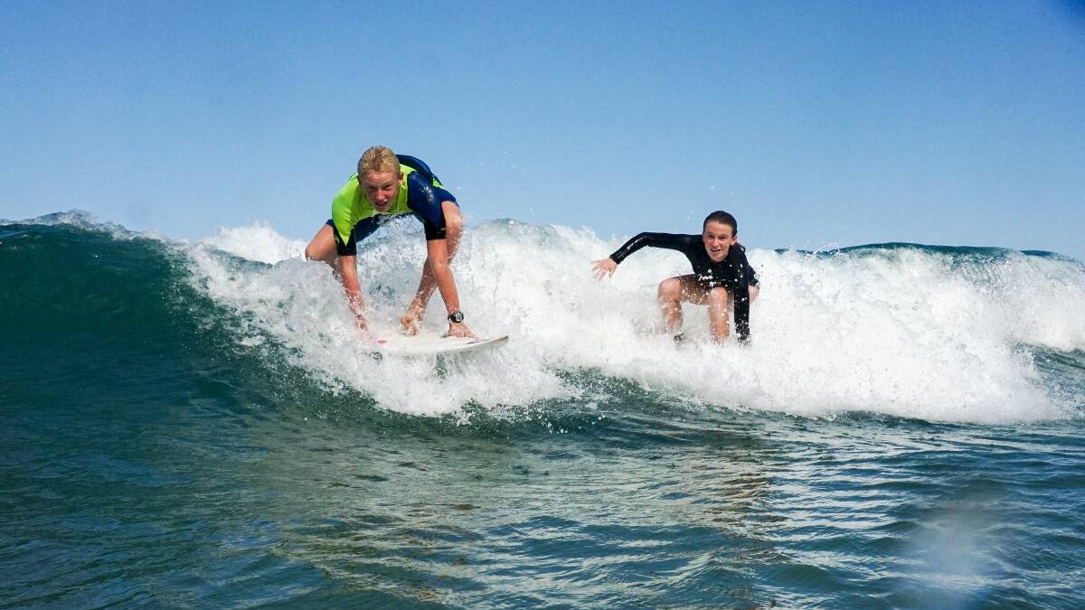 THEY'RE UP: Bulli siblings Anna and Aidan Chamberlain catch a wave at McCauleys Beach. Picture: Adam McLean