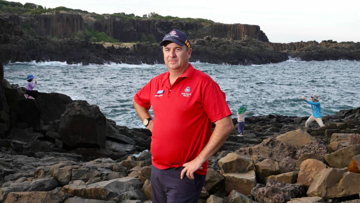 Surf Life Saving NSW South Coast duty officer Shane Wicks stands where the tragedy played out on Sunday. Behind him, an adult takes a photo of a child on the rocks. Picture Sylvia Liber