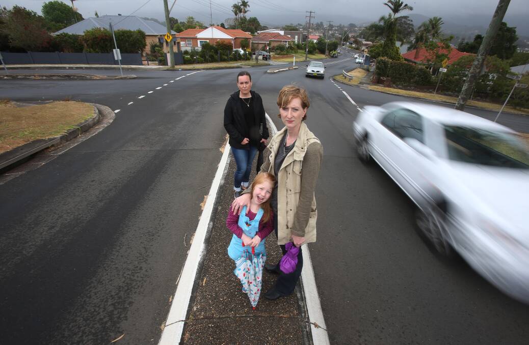 Mt St Thomas residents Marie Ivaneza and Madeleine and Alicia Thackray perched on The Avenue's thin pedestrian island. Ms Thackray is calling for a pedestrian crossing to be placed at the site. Picture: Robert Peet