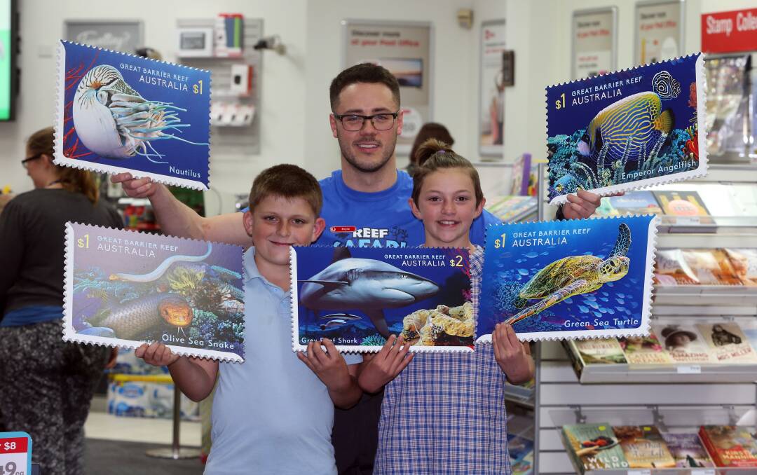 STAMP COLLECTING MONTH: Bryce Robertson from Australia Post with Berkeley West Public school twins Callum Yeaman and Caitlyn Yeaman. Picture: Robert Peet