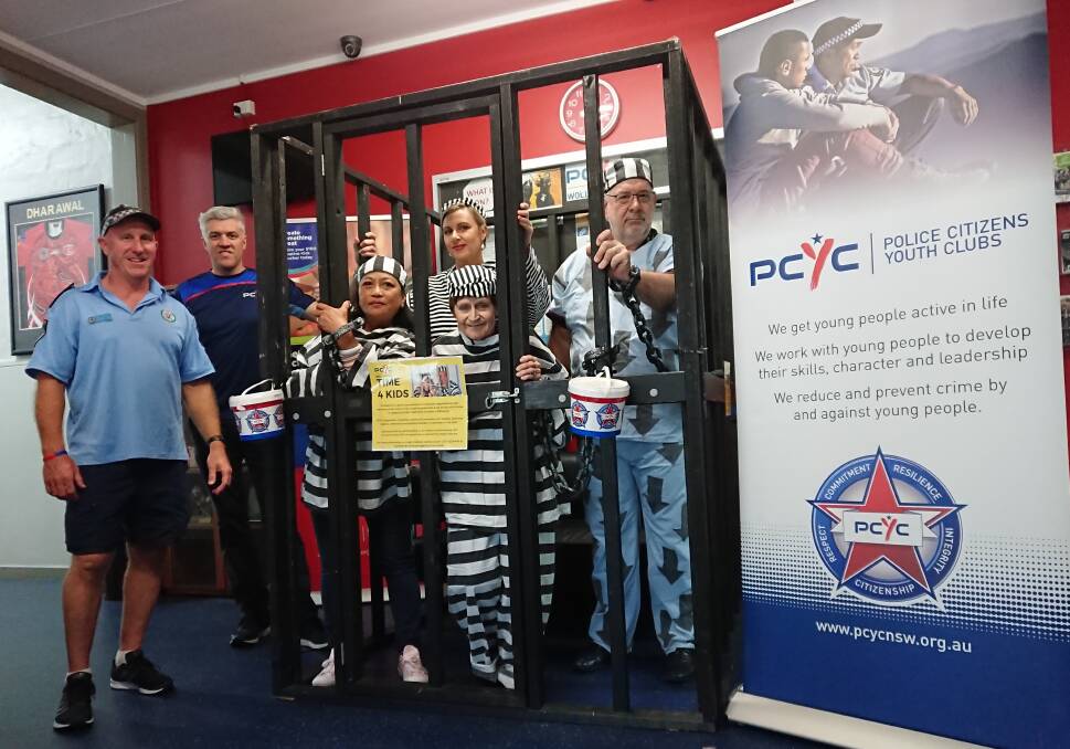 Get me outta here!: Senior Constable Darren Palk and PCYC manager Matt Bourne with some of Wollongong's business and community leaders "doing time" for kids.
