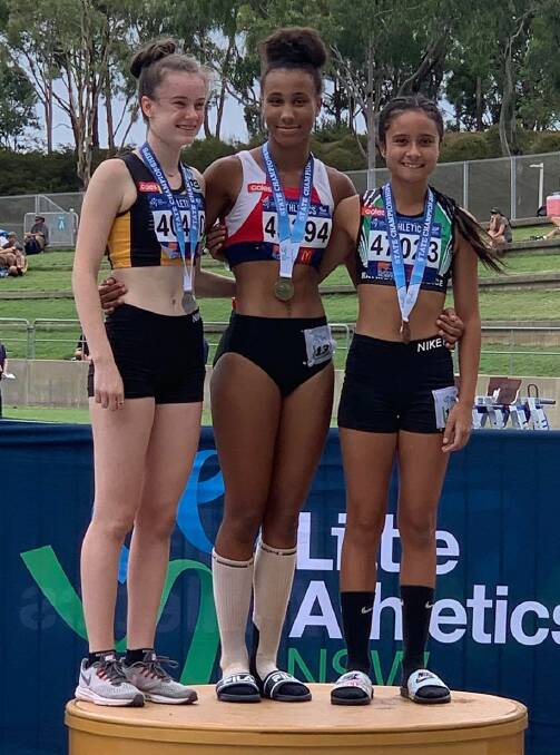 Future star: Chelsea Ezeoke (centre) on the podium with the gold medal she was awarded for the 100m (12.83 sec) at the NSW Little Athletics Championships.