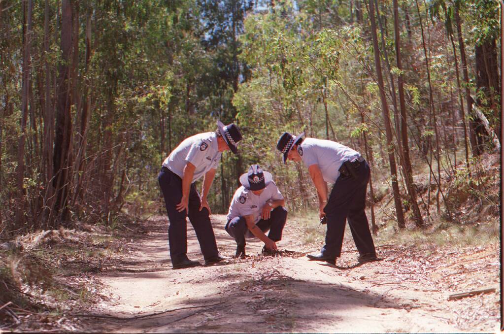 Victorian Police search a logging track near where the bodies of the two girls were found.