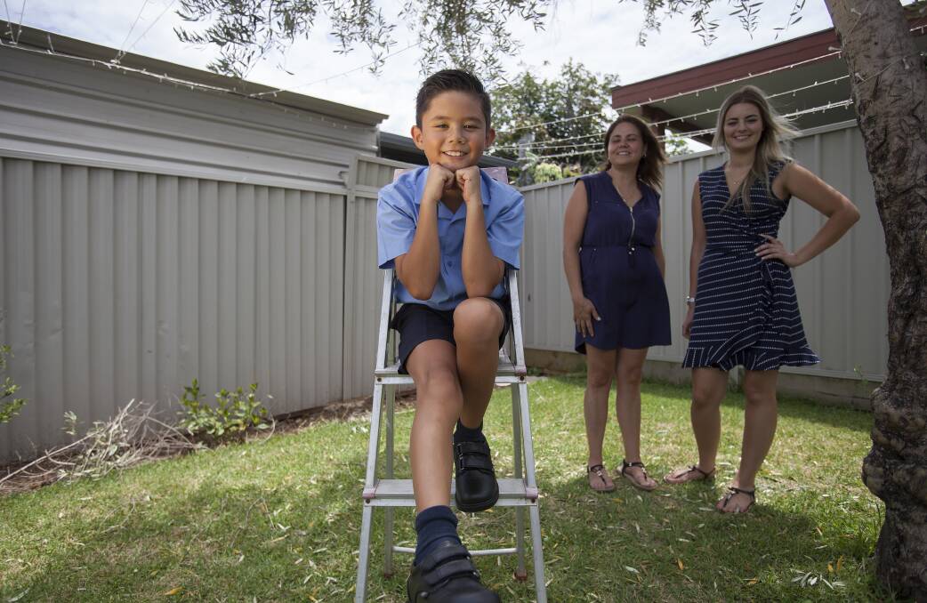 Fourth grader John-Paul in his new ROC school shoes at home with mum Alama and sister Mary-Therese. Photo: Fiona Morris