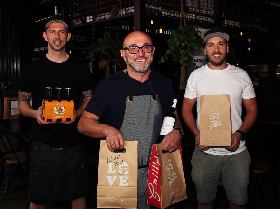 Special permission: Lube Markovski with his son-in-law Robert Gorgievski and son Allen Markovski standing two metres behind can now deliver a six pack of beer or bottle of wine with each Grill'd meal. 